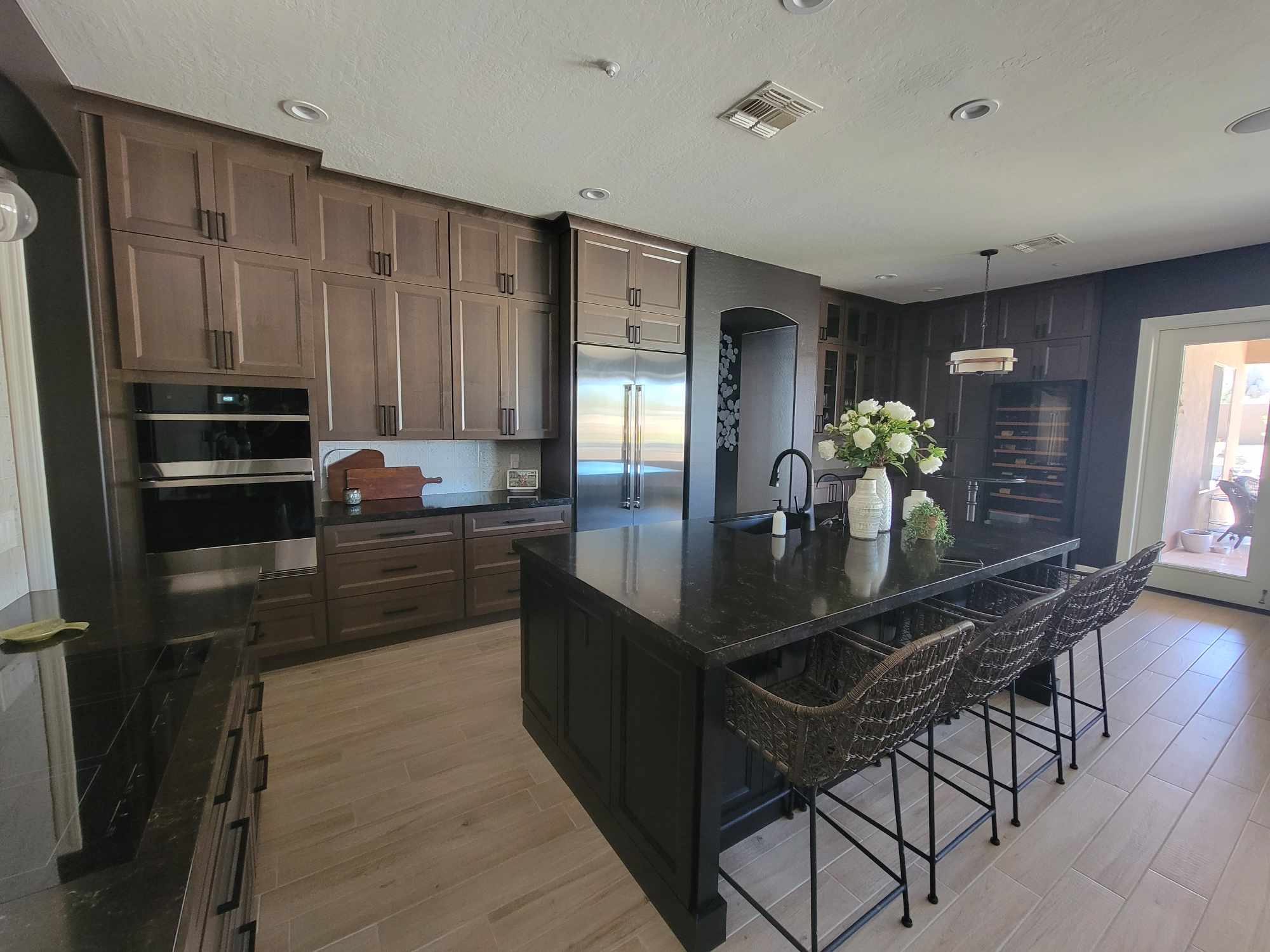 Modern kitchen in a Mesa, Arizona home with dark wood cabinets, a large black granite island, and stainless steel appliances.