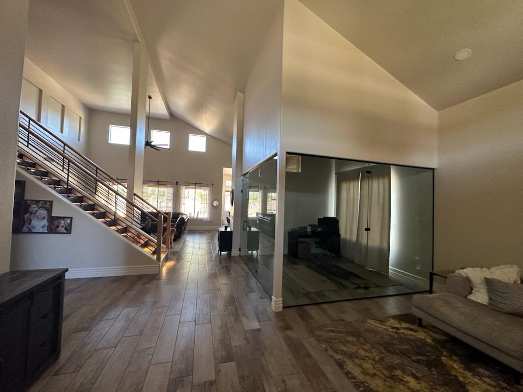 Bright, open-concept living space in a Tempe home with a staircase, high ceilings, and a glass-enclosed room.