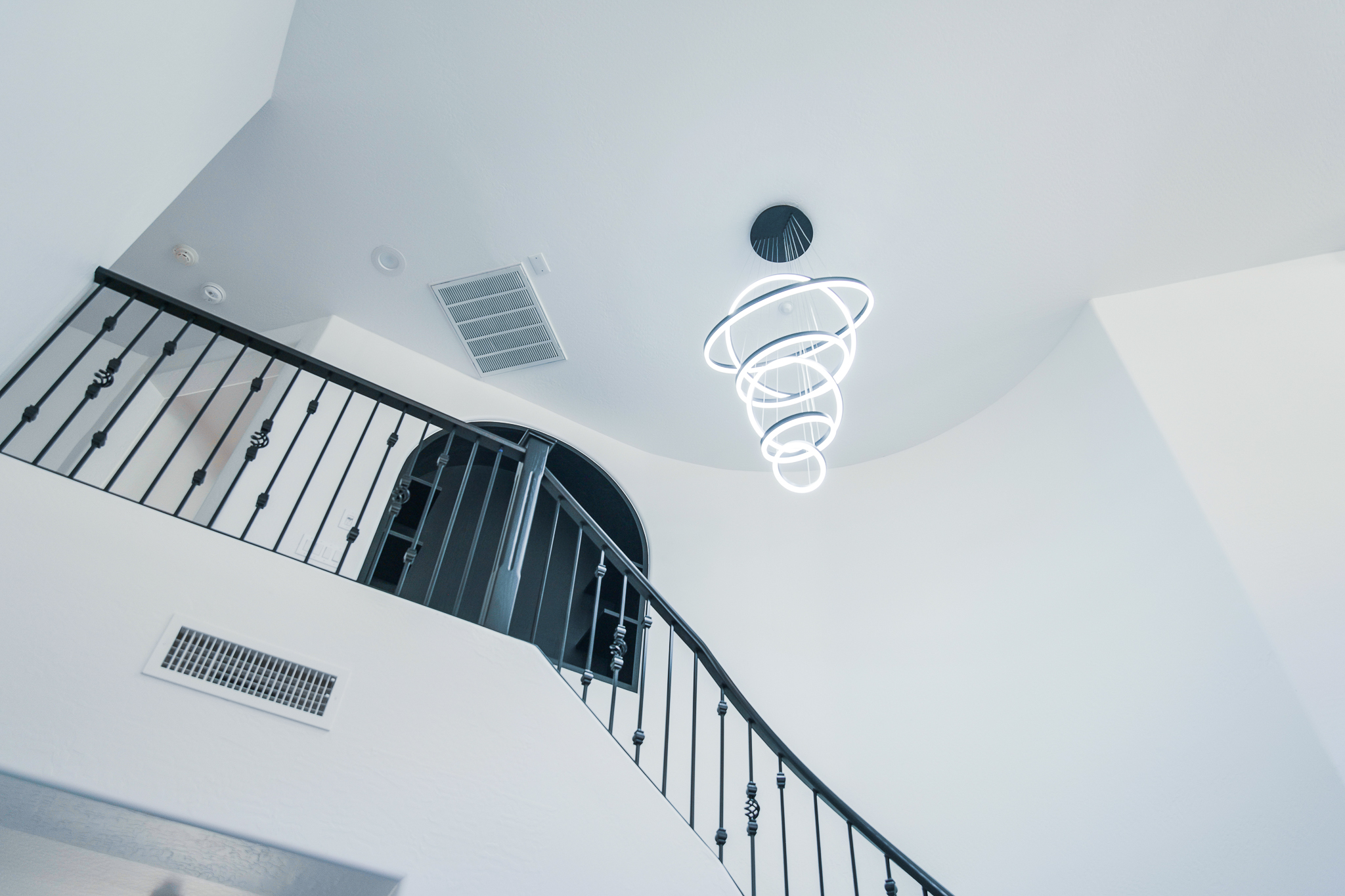 Unique spiral LED pendant light fixture with multiple illuminated rings in a contemporary home.