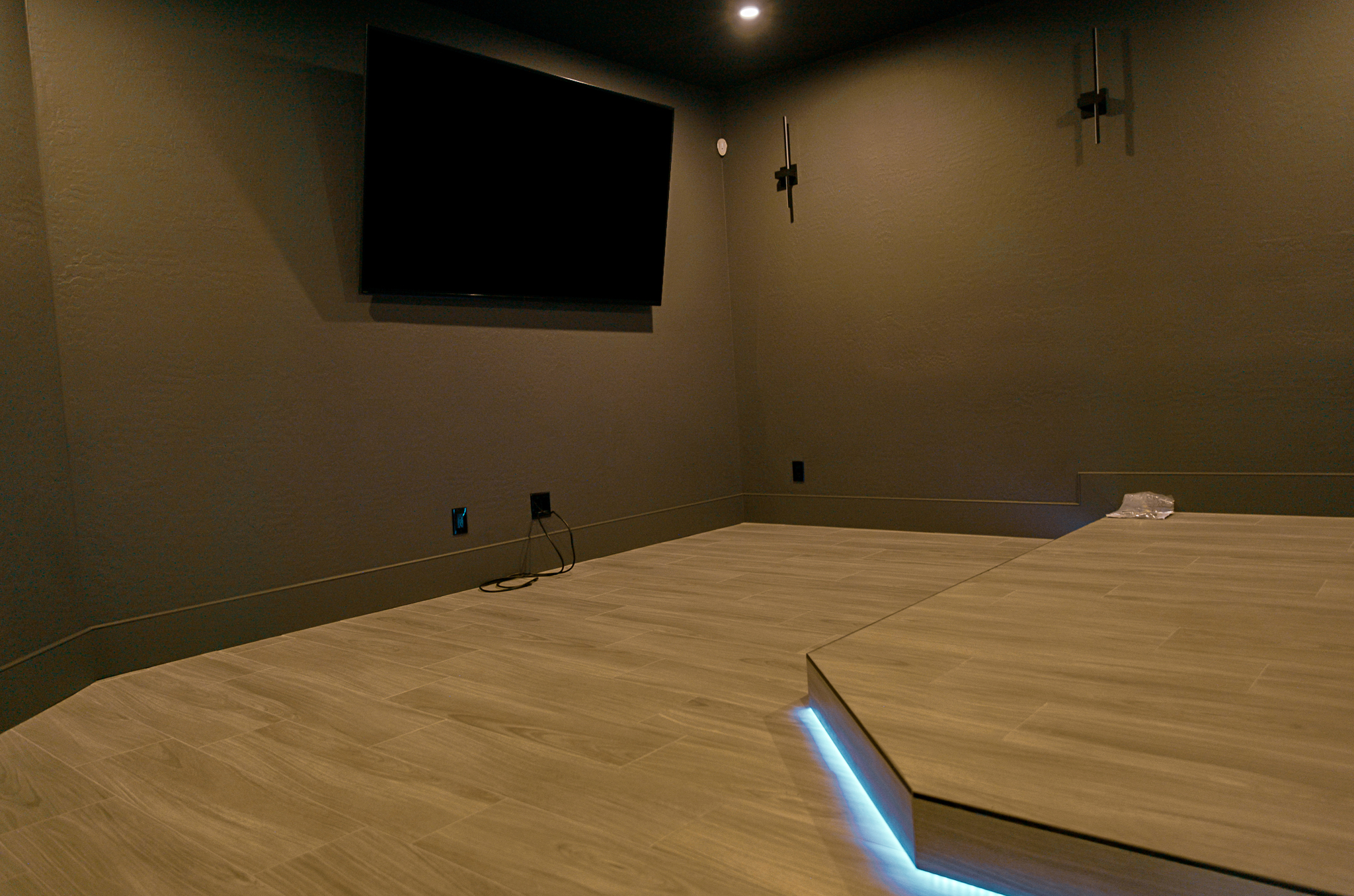 Contemporary home theater detail: a large flat-screen above a platform with blue underlighting.