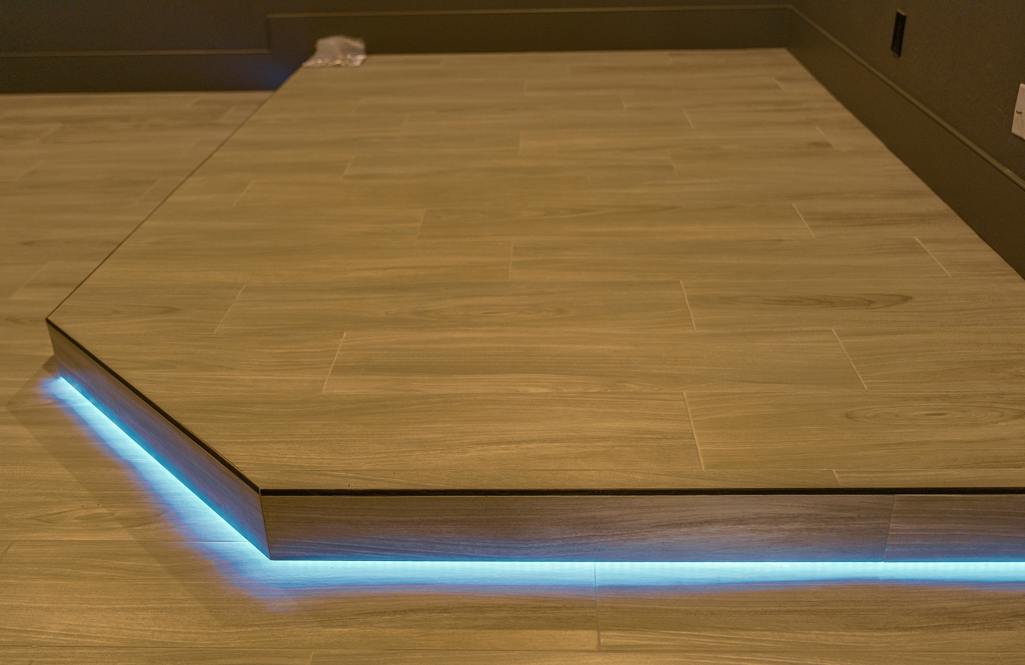 Elevated tiled floor section with ambient blue LED strip lights.
