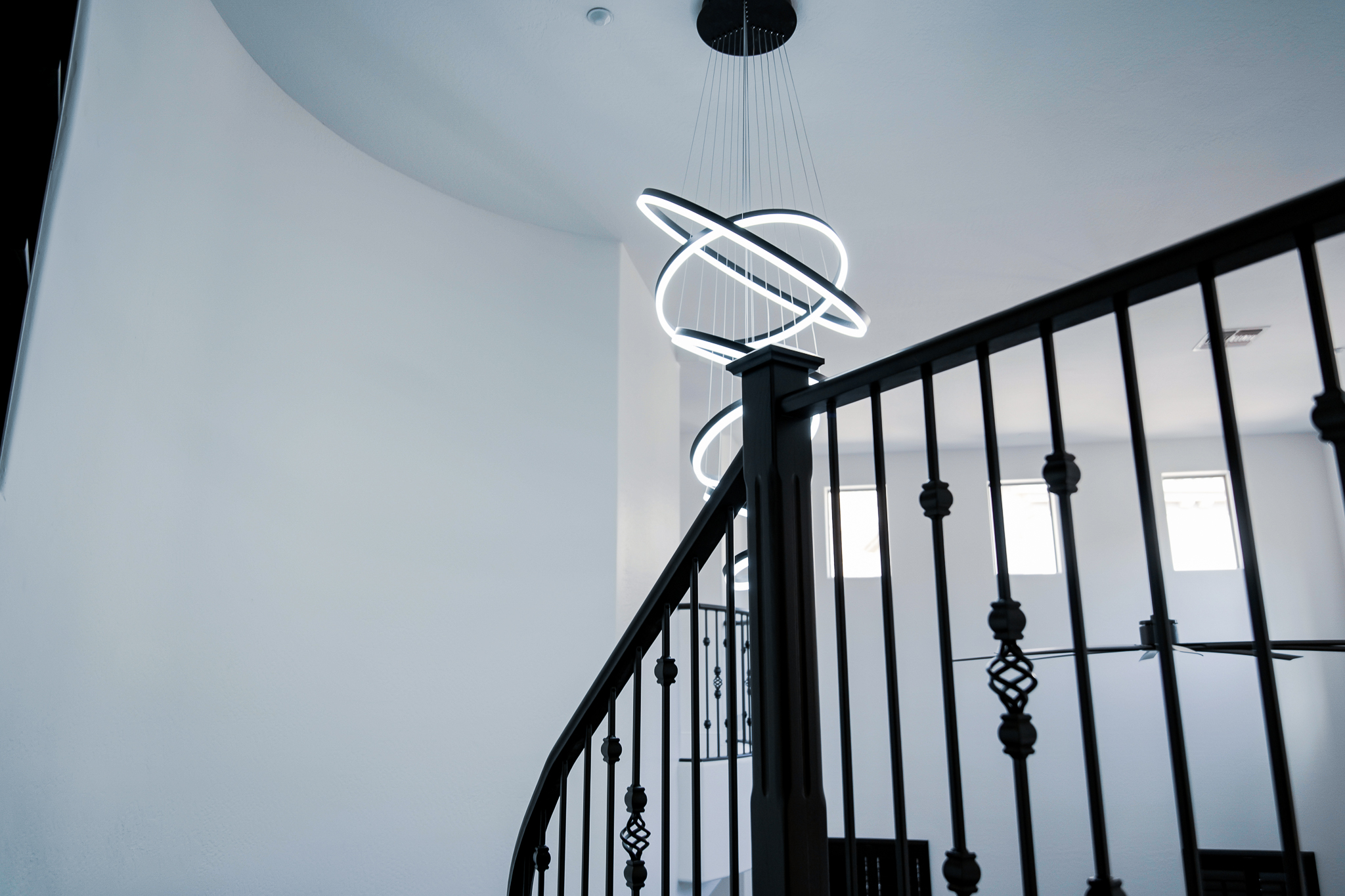 Abstract, circular LED lighting fixture cascades through a modern home's entryway in Tempe, Arizona, captured on a sunny afternoon.
