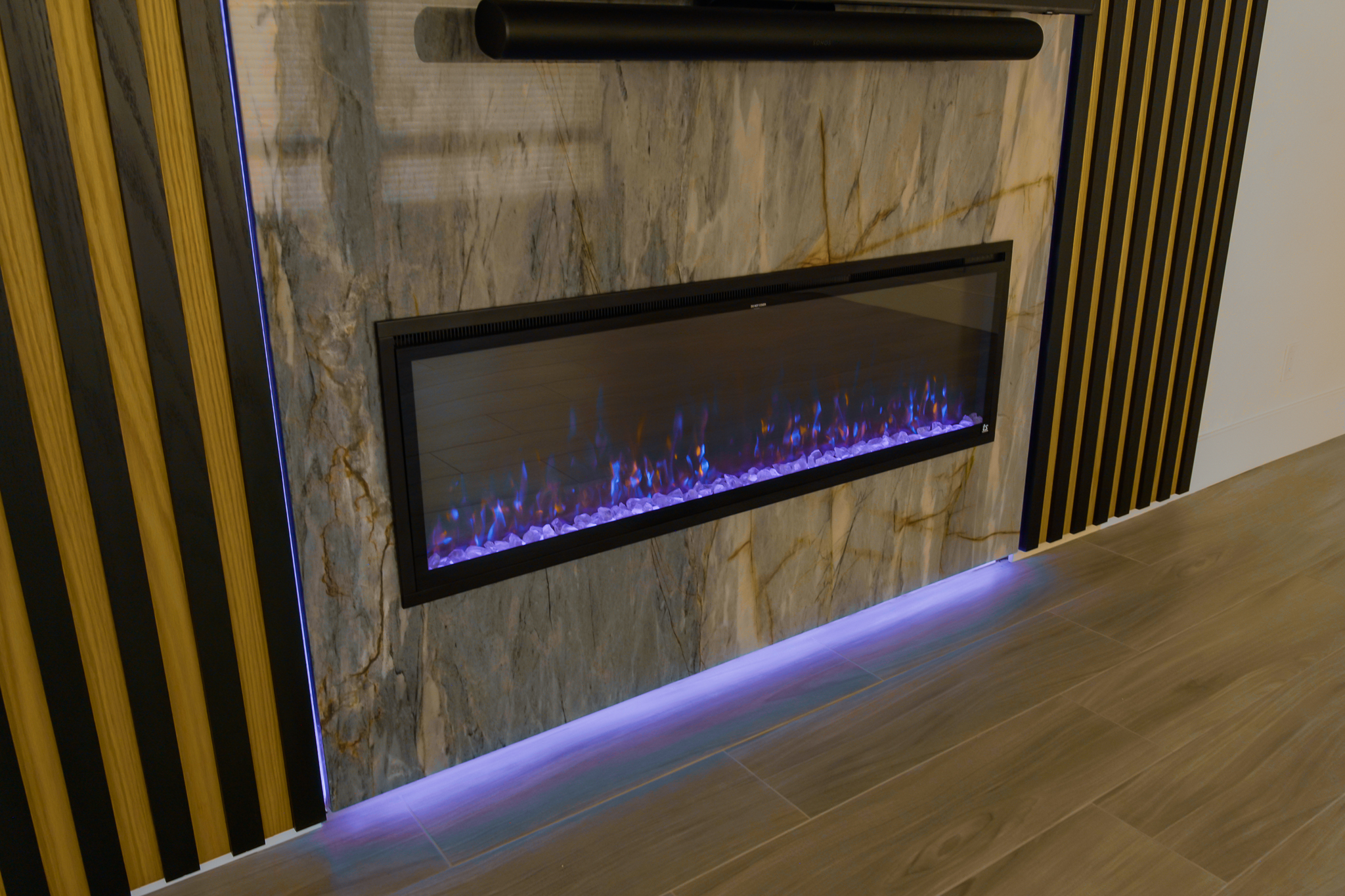 Modern black electric fireplace mounted on a marble wall with simulated flames.