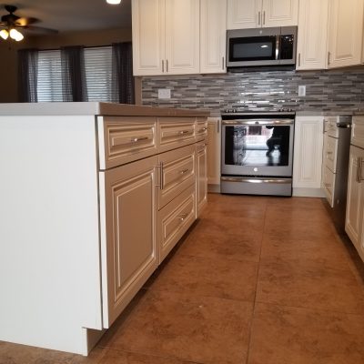 Kitchen with off-white glazed cabinets, light gray countertops, a mosaic tile backsplash, a stainless steel range, and a microwave above.
