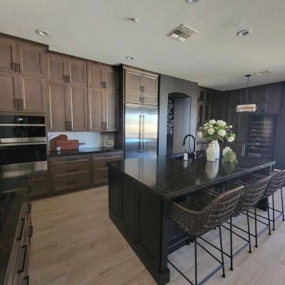 Modern kitchen in a Mesa, Arizona home with dark wood cabinets, a large black granite island, and stainless steel appliances.