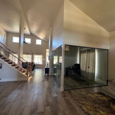 Bright, open-concept living space in a Tempe home with a staircase, high ceilings, and a glass-enclosed room.