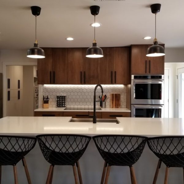 Modern kitchen in Tempe, Arizona, possibly remodeled by Five40 Remodeling LLC, with a large island, dark pendant lighting, and wood cabinets.