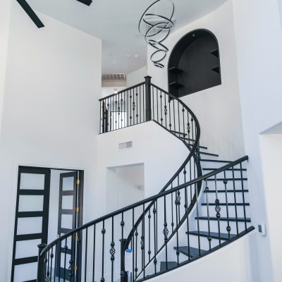 Wide view of a modern Tempe entryway featuring a wrought iron spiral staircase, a black Minka-Aire ceiling fan, and an Artemide Alphabet of Light chandelier.
