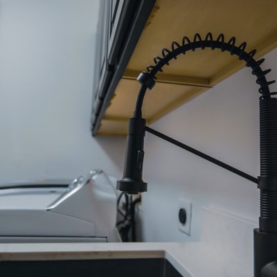 Modern black pull-down kitchen faucet over a dark sink, with a washing machine in the background.