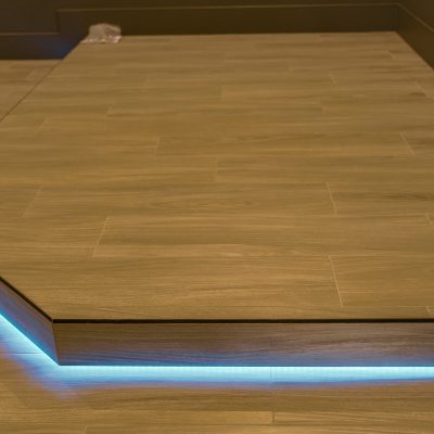 Elevated tiled floor section with ambient blue LED strip lights.
