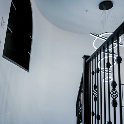Unique, spiraling LED pendant light with eight interconnected, glowing rings creates a contemporary focal point in a sunlit stairwell.