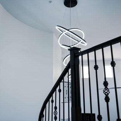 Abstract, circular LED lighting fixture cascades through a modern home's entryway in Tempe, Arizona, captured on a sunny afternoon.