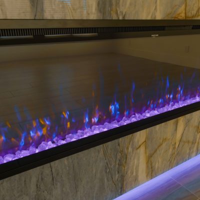 Modern black electric fireplace mounted on a marble wall with simulated flames.