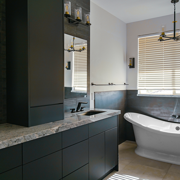 Modern bathroom in Tempe, Arizona, with dark vanity, granite countertop, freestanding tub, and contemporary lighting.